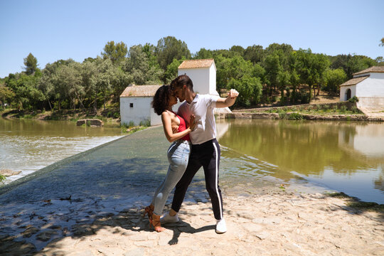 latin loving couple dancing social dance, kizomba, taraxia bachata, semba in the park next to the river and some big trees. Dance concept