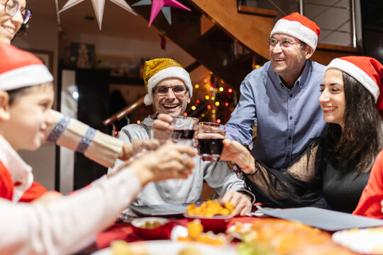 Happy Family Cheering With Wine Having Fun At Christmas Dinner Table