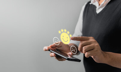 Businessman pressing face emoticon rating on virtual touch screen to service experience. Customer service and Satisfaction concept.