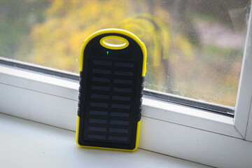 A yellow power bank with a solar battery during the day