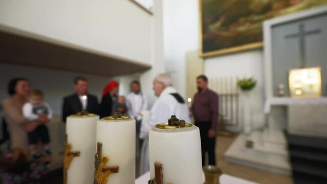 Blurry: Baptism process in a catholic church with priest and newborn's family