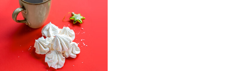Christmas background. A cup of coffee with marshmallows and meringue on a red background. Minimalism. Banner. Postcard. Copy space with a white sheet.
