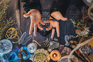 Hands making a magic gesture. Casting spells. Occult altar with crystals, snake skin, jewelry,...