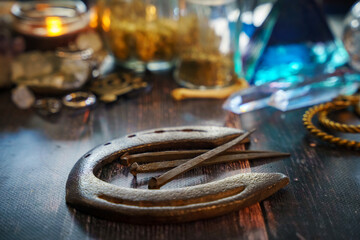 A very soft focus on traditional iron products. An old horseshoe and hand-forged antique nails from the 19th century. Concept of blurred mystical background with candles and potions on a wooden table.