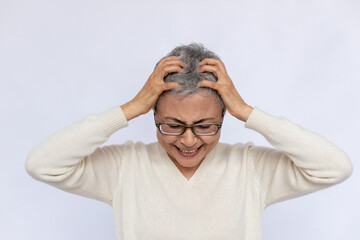 Portrait of frustrated senior woman holding head in hands. Mature Caucasian woman wearing eyeglasses and white jumper crying over white background. Despair, grief, trouble concept