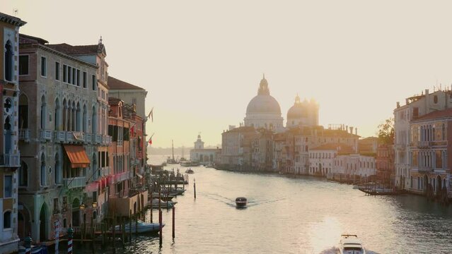 Sun rising over of Grand Canal traffic and Basilica di Santa Maria della Salute, view from Accademia bridge, Venice, Italy