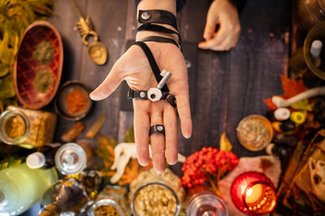 Hand holding an old key on the background of the occult altar. Preparing the Road Opener elixir,...