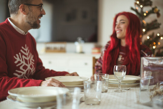 Man sitting at dining table a Christmas with his adult daughter