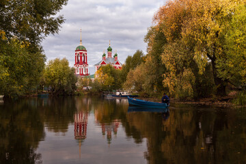 Russian church is reflected in pond surrounded by colorful autumn trees, Pereslavl-Zalessky, Russia
