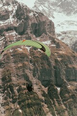 High angle shot of a man paragliding in the air on the background of mountains