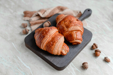 Delicious crispy croissant with chocolate with a cup of invigorating coffee on a light concrete background