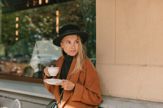 Portrait of a beautiful woman standing outside a cafe drinking a cup of coffee