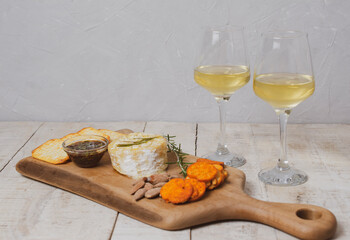 French camembert cheese baked in the oven with rosemary, cranberry and honey sauce, served with nuts and bruschetta on a wooden board.  Served with white wine. Copy space