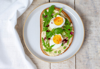 Boiled egg on bread with arugula. Healthy food