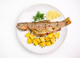 Baked trout with potato in plate. Isolated on white background.