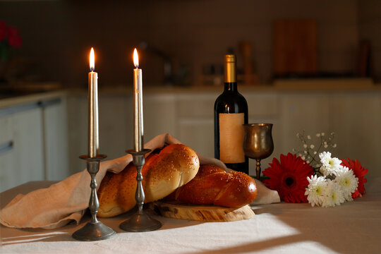 Challah bread covered with a special napkin, shabbat wine  on the kitchen table. Traditional Jewish Shabbat ritual. Shabbat Shalom.