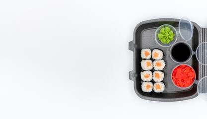 Copyspace of salmon maki sushi in delivery box on white background