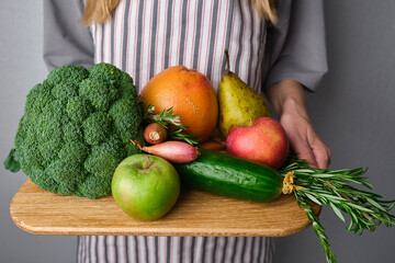 A woman holds a set of fresh vegetables and fruits in her hands. Vegetables close-up. Natural fresh organic vegetables. Healthy food, raw food diet. Vegetarian life. Proper nutrition. Ready to eat