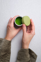 Matcha green tea powder in a jar in the hands of a girl. Organic Green Matcha Tea ceremony. Cooking with matcha, recipe
