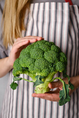 A woman holds green broccoli in her hands. Broccoli close up. Natural fresh organic vegetables. Healthy food, raw food diet. Vegetarian life. Proper nutrition. Ready to eat. Eco product