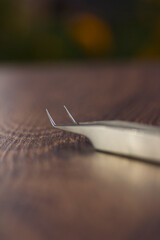 Silver eyelash extension tweezers close-up on a wooden background
