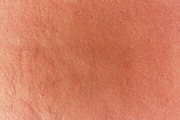 A red plaster wall with a rough surface in daylight