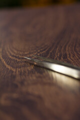 Silver eyelash extension tweezers close-up on a wooden background