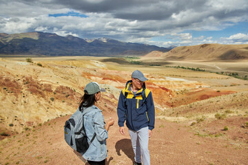 man and woman tourists on background of desert and hilly landscape on summer day. Sights of Russia, Siberia and Altai Republic, mars. Tourism and travel. Kosh-agach, Chagan-Uzun