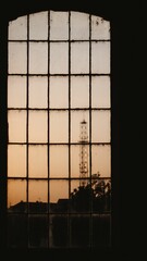 Vertical shot of an old window with a tower in the distance