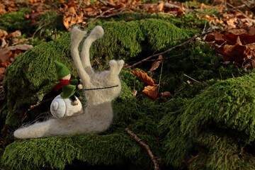 Filzwichtel reitet auf Filzschnecke durch den Wald.
