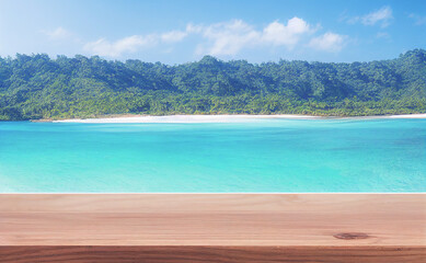 Empty wooden table for product display with view of tropical beach background.