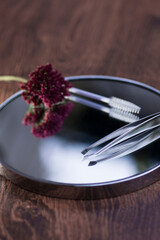 Eyebrow tweezers, brush and flower reflected on the mirror