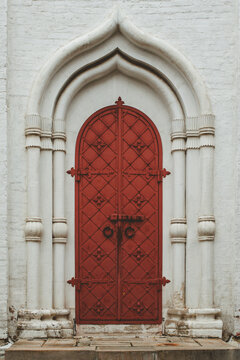 Old metal red door. Vintage iron doors. Big wrought iron door leafs. entrance with arch aperture from a white stone to the madieval monastery