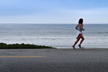 Caucasian female running on a road along the ocean in California, USA