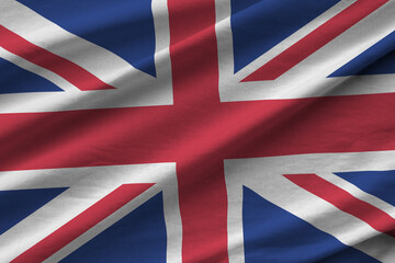 Great britain flag with big folds waving close up under the studio light indoors. The official...