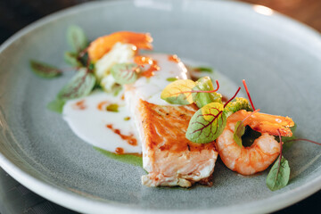 Salmon steak covered in cream sauce, garnished with shrimp and red caviar. Restaurant service.