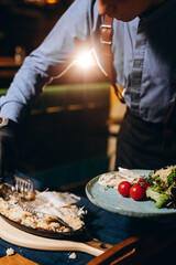 Fish baked in salt. The waiter cuts the fish into pieces. Restaurant concept.