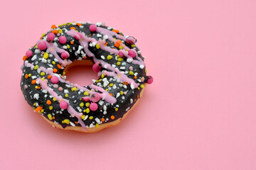 donut with colorful icing on pink background, copy space