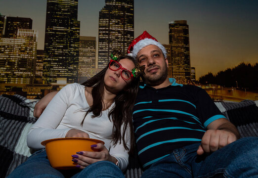 Woman and man are watching movie at home in Christmas decorations, eating popcorn. Selective focus. Picture for website about family, movies, Christmas.