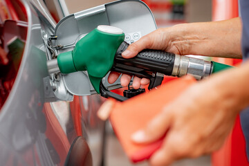 Woman with wallet in hand while filling fuel into the car tank at the pump service station, for the rising prices of the energy concept transportation business