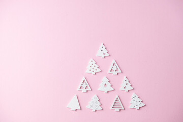 small white Christmas tree figurines laid out in the shape of a Christmas tree on a pink background with a place for text , Christmas concept, gifts,sale