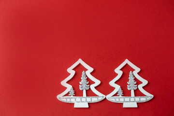 Fototapeta na wymiar small white figures of a Christmas tree on a red background with a place for text, Christmas concept, gifts,sale