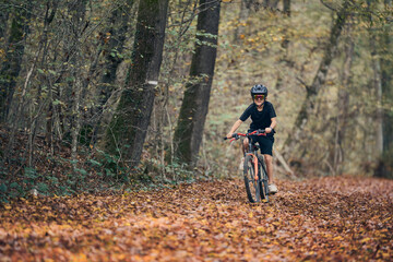 Enfant en v&eacute;lo dans les bois en automne
