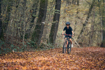 Fototapeta na wymiar Enfant en vélo dans les bois en automne