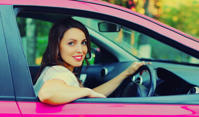 Fototapeta na wymiar Portrait of happy smiling woman driver behind a wheel car