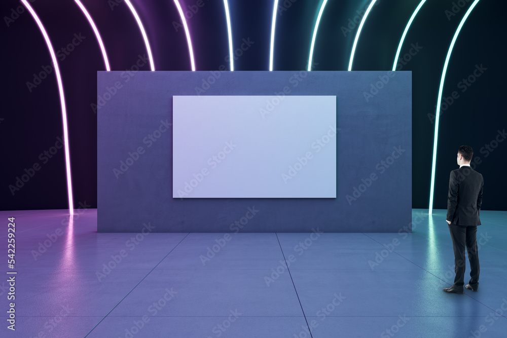 Poster businessman back view looking at blank white poster with space for your logo or text on dark partiti