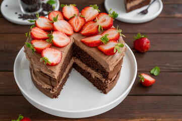 Naked chocolate cake with cream and fresh strawberries on top. Rustic style. Selective focus. Copy space.