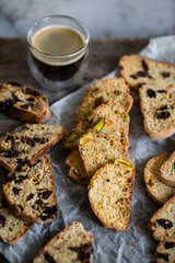 Christmas cookies. Heap of three different kinds of biscotti (chocolate, dried fruits, pistachio) and glass of espresso on wooden table.