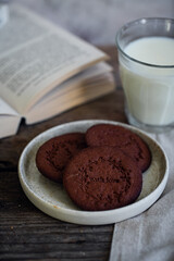  Norwegian Christmas spiced cookies pepperkaker with glass of milk and open book on wooden table .