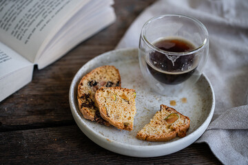 Glass of espresso coffee and homemade biscottis on plate on wooden table.